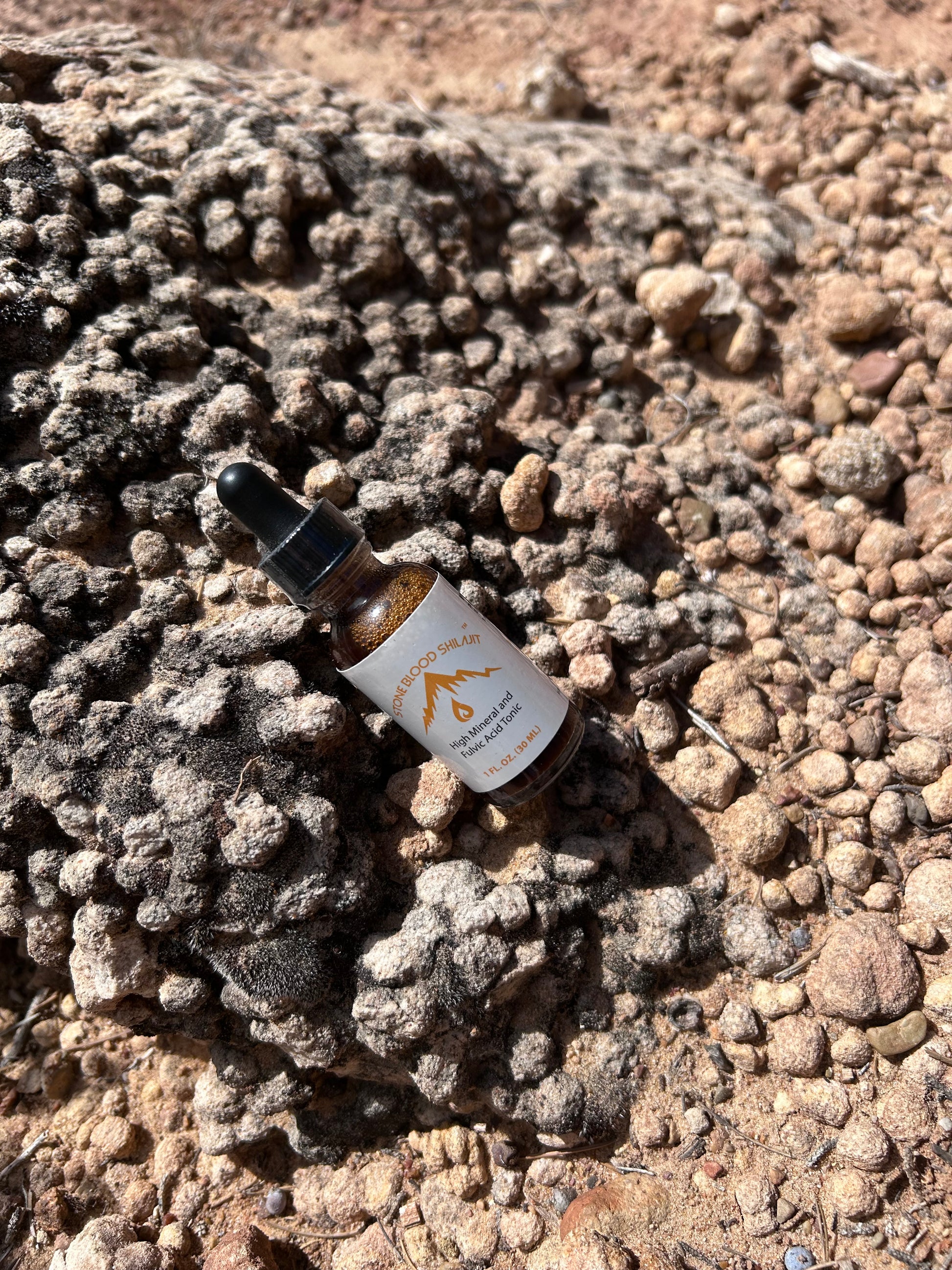 Stoneblood Shilajit dropper bottle resting on raw mineral resin rock, wildcrafted in the Utah desert