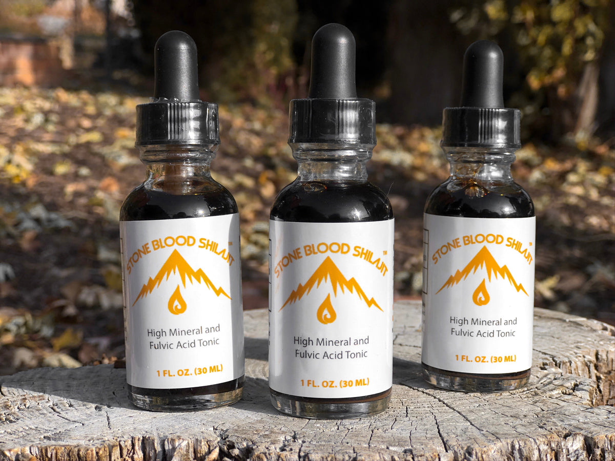 Three bottles of Stoneblood Shilajit Original on a tree stump